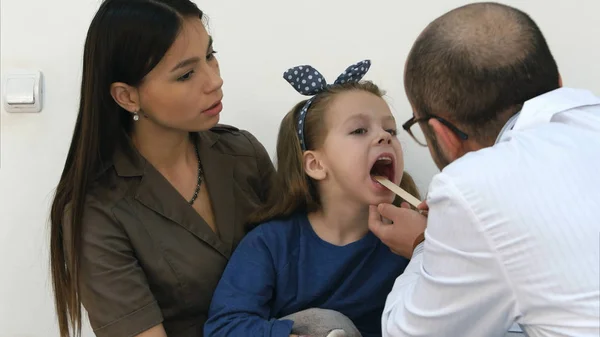 Mała dziewczynka o badanie gardła lekarz mężczyzna — Zdjęcie stockowe