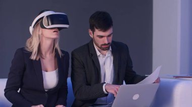 İnşaat proje planları laptop önünde tutarak onun ortağı ile tartışırken vr kulaklık sarışın kadın