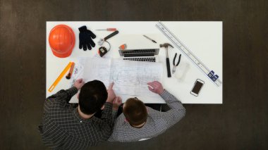 Çizimler ve planları tartışan iki erkek mimarlar