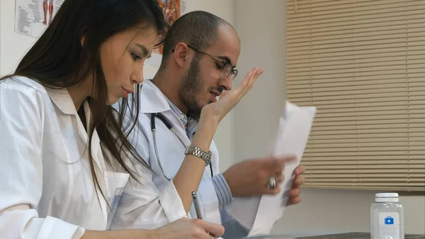 Enfermera joven y médico varón discutiendo en el consultorio — Foto de Stock