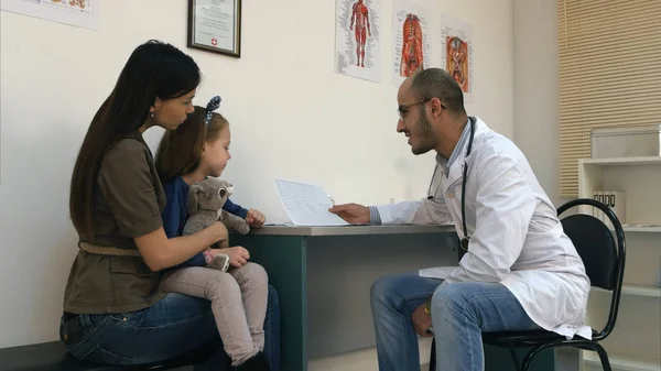 Dottore sorridente che spiega il cardiogramma alla madre e alla bambina — Foto Stock