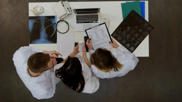 Медицинская команда обсуждает, какие таблетки назначать с помощью ноутбука — стоковое фото