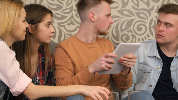 Friends gathering at home and using tablet