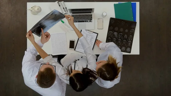 Tres médicos jóvenes mirando la radiografía de columna — Foto de Stock