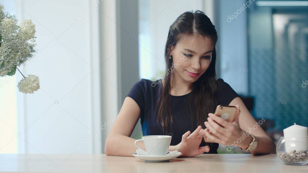 Happy female watching her photos on cell phone in coffee shop