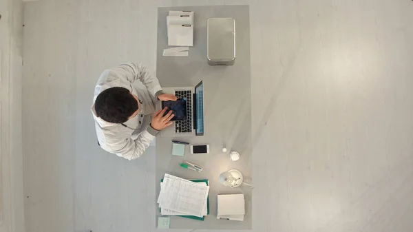 Врач мужского пола работает за столом с ноутбуком. Вид сверху — стоковое фото