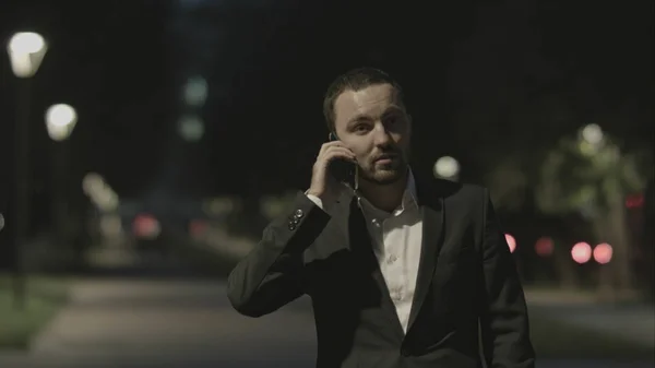 Empresario amable hablando por teléfono en el parque de la ciudad de buen humor . — Foto de Stock