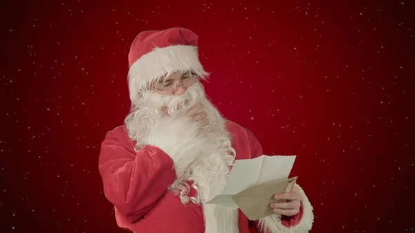 Santa Claus leyendo cartas de niños sobre fondo rojo con nieve —  Fotos de Stock