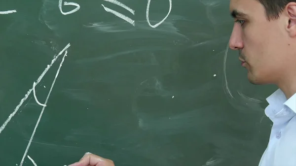 Молодой учитель или ученик рисует треугольник на доске с формулой — стоковое фото