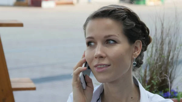Красивая молодая женщина улыбается, звоня кому-то через мобильный телефон . Стоковая Картинка