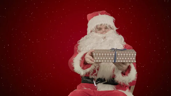 Santa Claus: Hadiah ceria dengan latar belakang merah dengan salju Stok Foto