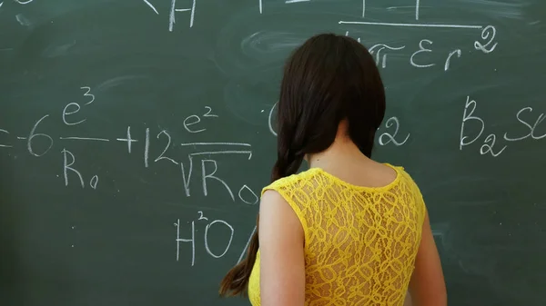 Mahasiswa muda menulis di papan tulis atau papan tulis selama kelas matematika Stok Foto Bebas Royalti