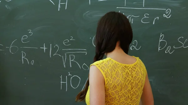 Joven estudiante universitario escribiendo en la pizarra o pizarra durante una clase de matemáticas Fotos de stock libres de derechos