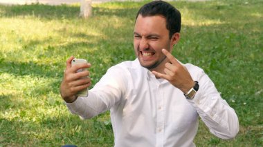 Bir cep telefonu, yaz Parkı açık havada selfie resimleri alarak genç iş adamı