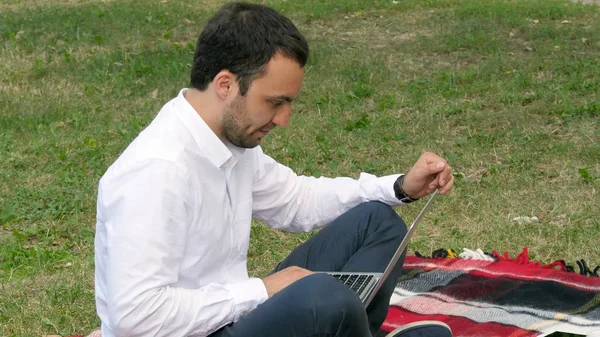 Un joven sonriente hombre con portátil al aire libre — Foto de Stock