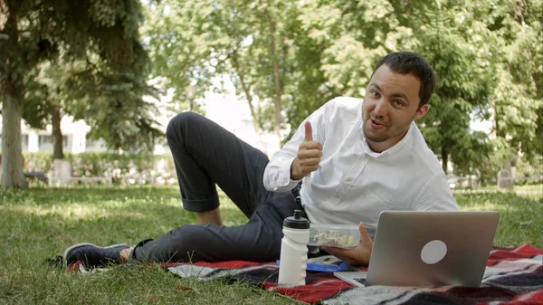 Hombre atractivo a la hora del almuerzo en el parque, decir algo en la cámara — Foto de Stock
