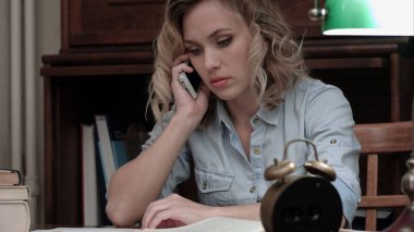 Endişeli kadın onun işyerinde oturan telefonda konuşuyor