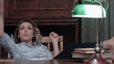 Hayal kırıklığına uğramış genç işkadını atma kağıt bacaklarını masaya oturuyor