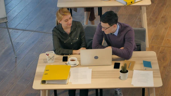 Молодая пара работает вместе над ноутбуком в офисе — стоковое фото