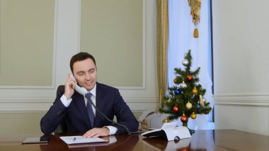 Gülümseyen işadamı malzeme çekme belgili tanımlık telefon yukarıya ve iş arkadaşları ile Noel kutladı