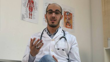 Kameraya konuşurken stetoskop ile olumlu erkek Arap doktor