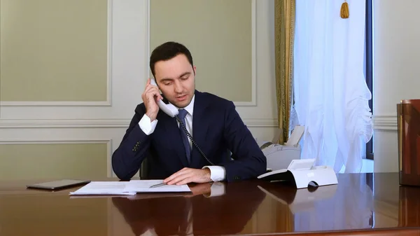 Serious businessman discuss problem by landline phone and becomes disappointed
