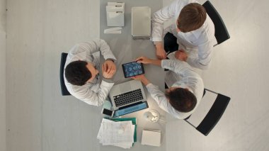 Tıbbi ofiste Tablet PC bilgisayarları toplantı ile mutlu doktorlar grubu. Üst görünüm
