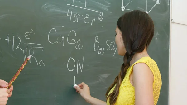 Estudiante escribiendo símbolo químico en pizarra . — Foto de Stock