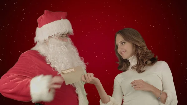 크리스마스 편지 또는 빨간색 배경에 눈에 위시 리스트를 읽고 그의 여성 도우미와 함께 행복 한 산타 클로스 — 스톡 사진