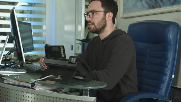 Vista lateral de un trabajador de oficina masculino que trabaja en una computadora en una oficina brillante — Foto de Stock