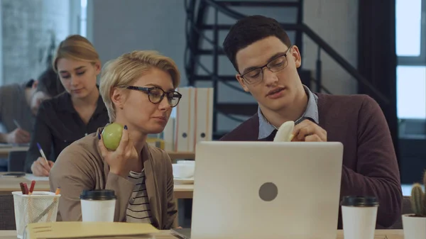 Jóvenes socios de negocios están descansando en la oficina, comiendo frutas y hablando — Foto de Stock