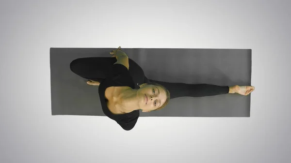 Ritratto di una giovane donna che allunga il corpo, guardando la macchina fotografica sopra su sfondo bianco — Foto Stock