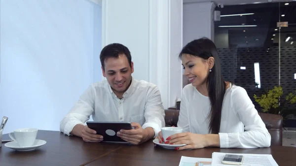 Pareja joven riendo de algo divertido en la tableta esperando su almuerzo — Foto de Stock