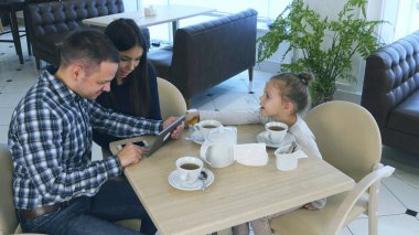 Kızları kafede onların dikkatini çekmek isterken tablet vasıl seyir ebeveynler harcama zaman.