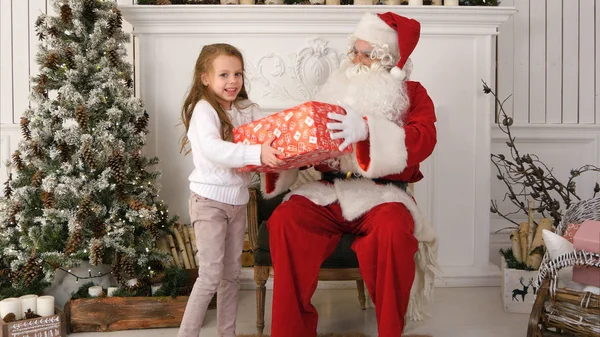 Τον Άγιο Βασίλη δίνοντας ένα δώρο τυλιγμένο όμορφα σε ένα χαριτωμένο κοριτσάκι — Φωτογραφία Αρχείου