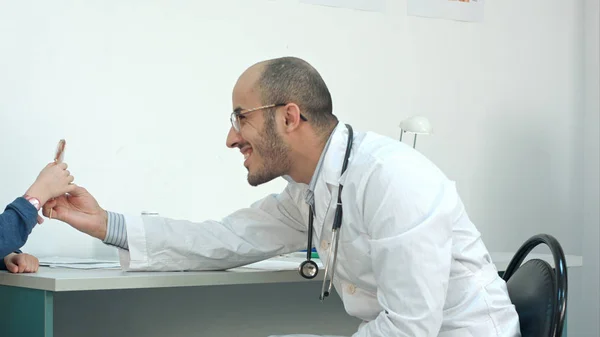 Médico sorrindo dando pouco paciente um chupa-chupa após o exame — Fotografia de Stock