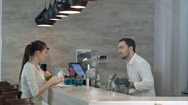 Barista sonriente y joven mujer bonita hablando en la cafetería — Foto de Stock