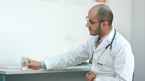 Чоловік лікар описує діагноз і показує пляшку таблеток своєму пацієнту — стокове фото