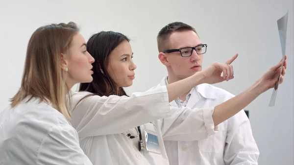 Three young doctors looking at spine x-ray — Stock Photo, Image