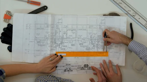 Молодые архитекторы проверяют размеры чертежей с помощью делителя и линейки — стоковое фото