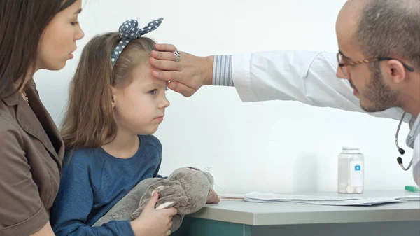 男性の小児科医が発熱のため小さな女の子の頭をチェック — ストック写真