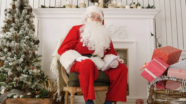 Nevetve Santa ül egy széken, karácsonyi műhelyében — Stock Fotó