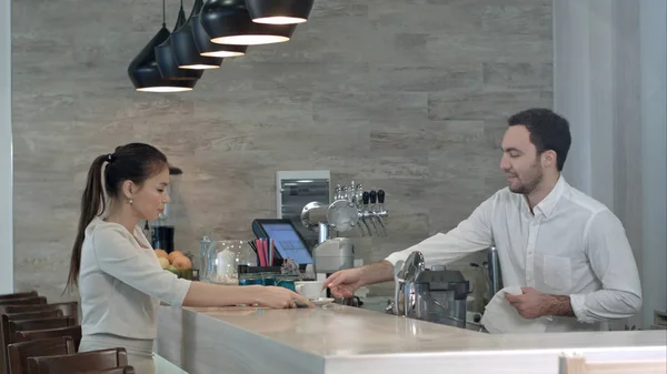 Barista sonriente hablando con una clienta terminando su bebida — Foto de Stock