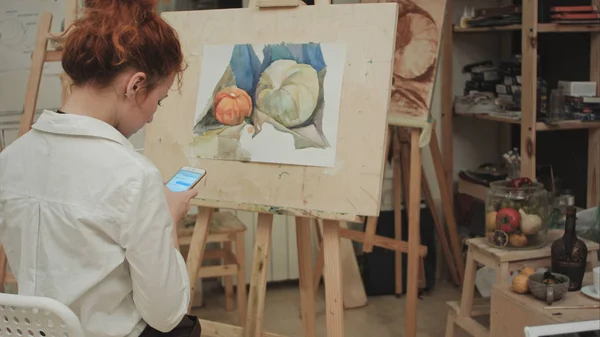 Női festő használ smartphone, workshop — Stock Fotó