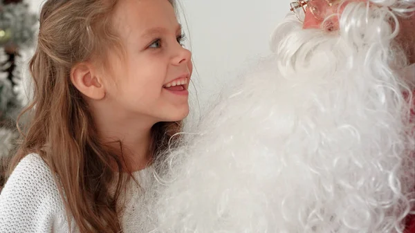 Χαμογελαστός και ντροπαλό κορίτσι που μοιράζονται τα χριστουγεννιάτικα όνειρα με Σάντα — Φωτογραφία Αρχείου