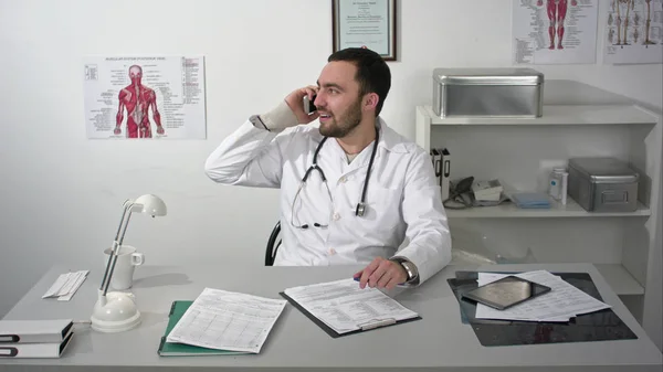 Freundlicher Arzt, der per Smartphone mit jemandem spricht — Stockfoto