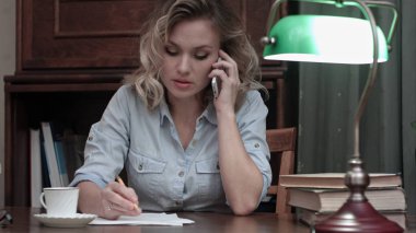 İş telefonda konuşurken ve notlar masasında yapma genç kadın konsantre