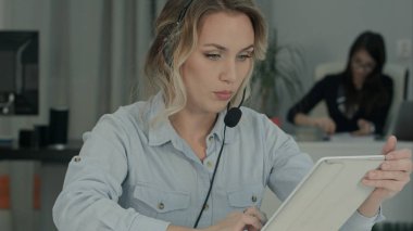 Meşgul Çağrı Merkezi müşteri temsilcisi bir çağrı onun işyerinde dijital tablet kullanma