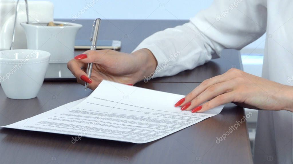 Woman hand with red nails signing contract