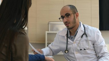 Anne ve çocuk için tanı açıklayan gözlüklü genç doktor